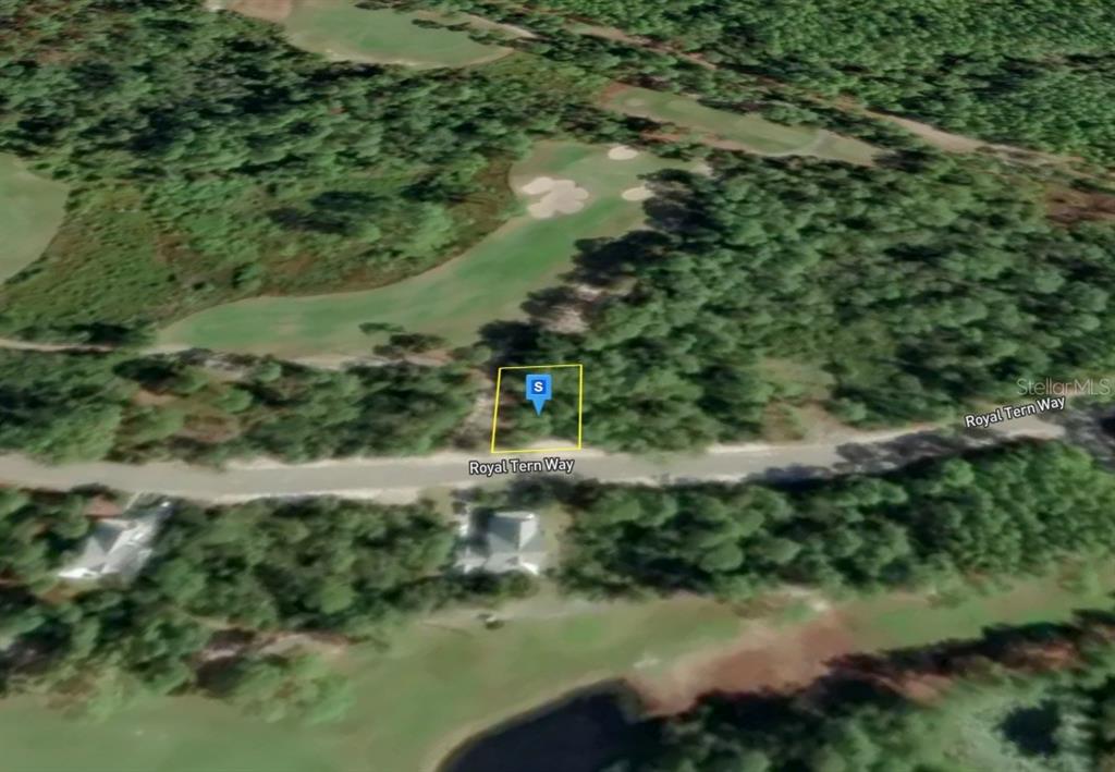 An aerial view shows a vacant lot on a road bordering a golf course — 214 ROYAL TERN WAY, CARRABELLE, FL