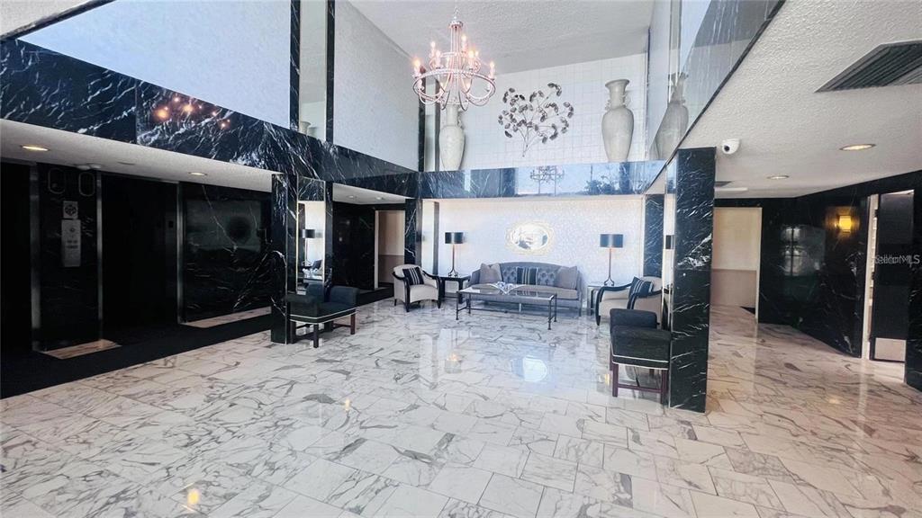 A spacious lobby features black marble accents, white marble flooring, and a central seating area — 100 PIERCE STREET UNIT 1001, CLEARWATER, FL