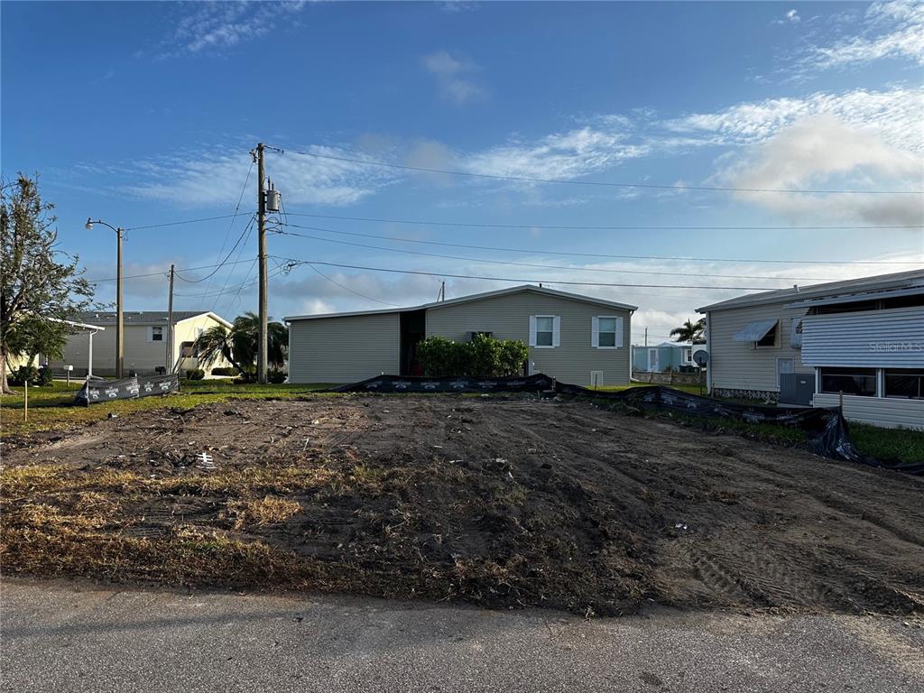 A vacant, cleared residential lot sits between two existing manufactured homes under a blue sky — 269 JAMAICA DRIVE, PALMETTO, FL