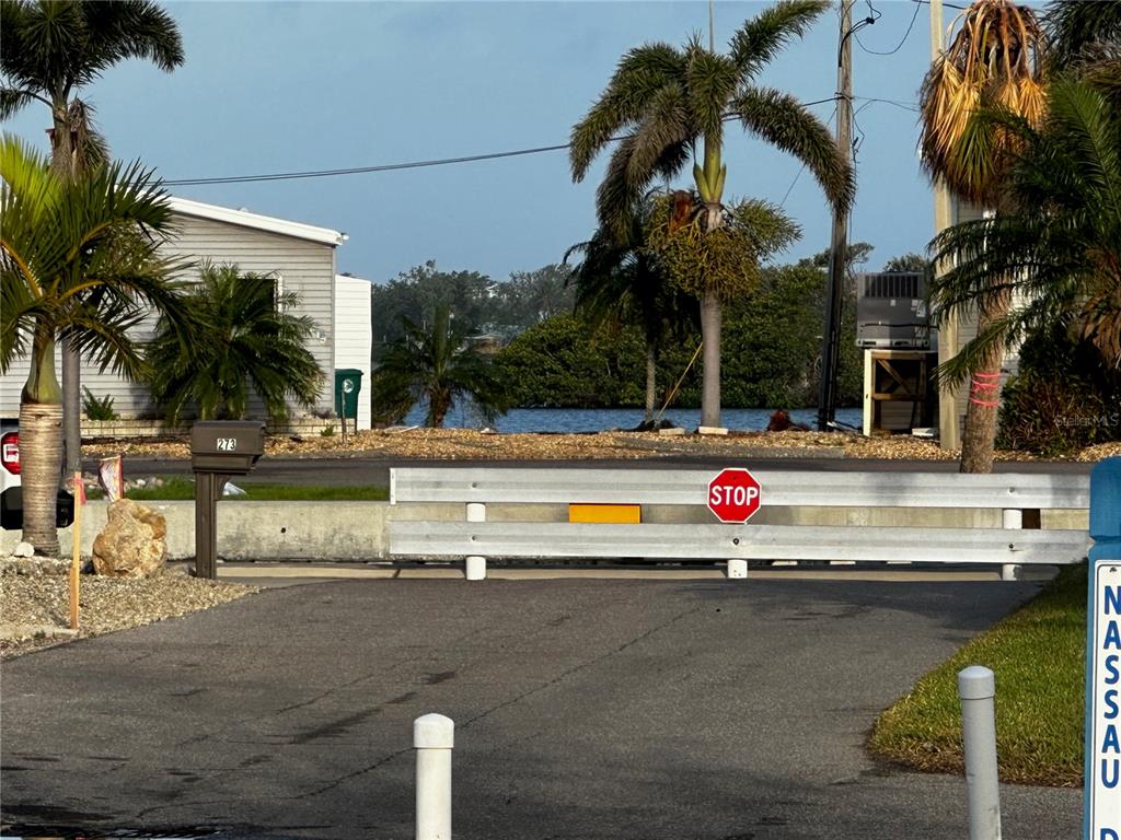 A paved road leads to a metal barrier with a stop sign near a waterfront area — 269 JAMAICA DRIVE, PALMETTO, FL