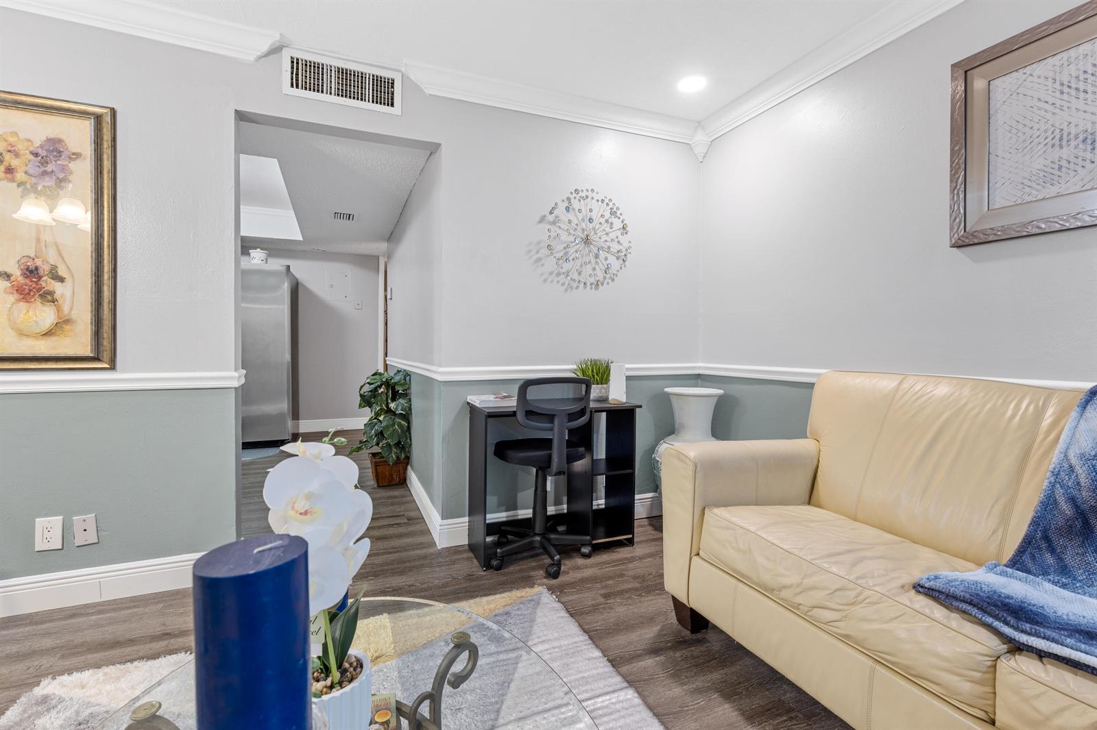 A living area features a beige leather sofa, a small desk, and two-toned gray walls — 101 NE 4th Street # 3, Delray Beach FL 33444, DELRAY BEACH, FL