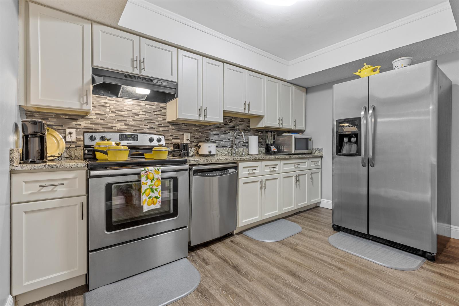 A kitchen features stainless steel appliances, light-colored cabinets, granite countertops, and a tiled backsplash — 101 NE 4th Street # 3, Delray Beach FL 33444, DELRAY BEACH, FL