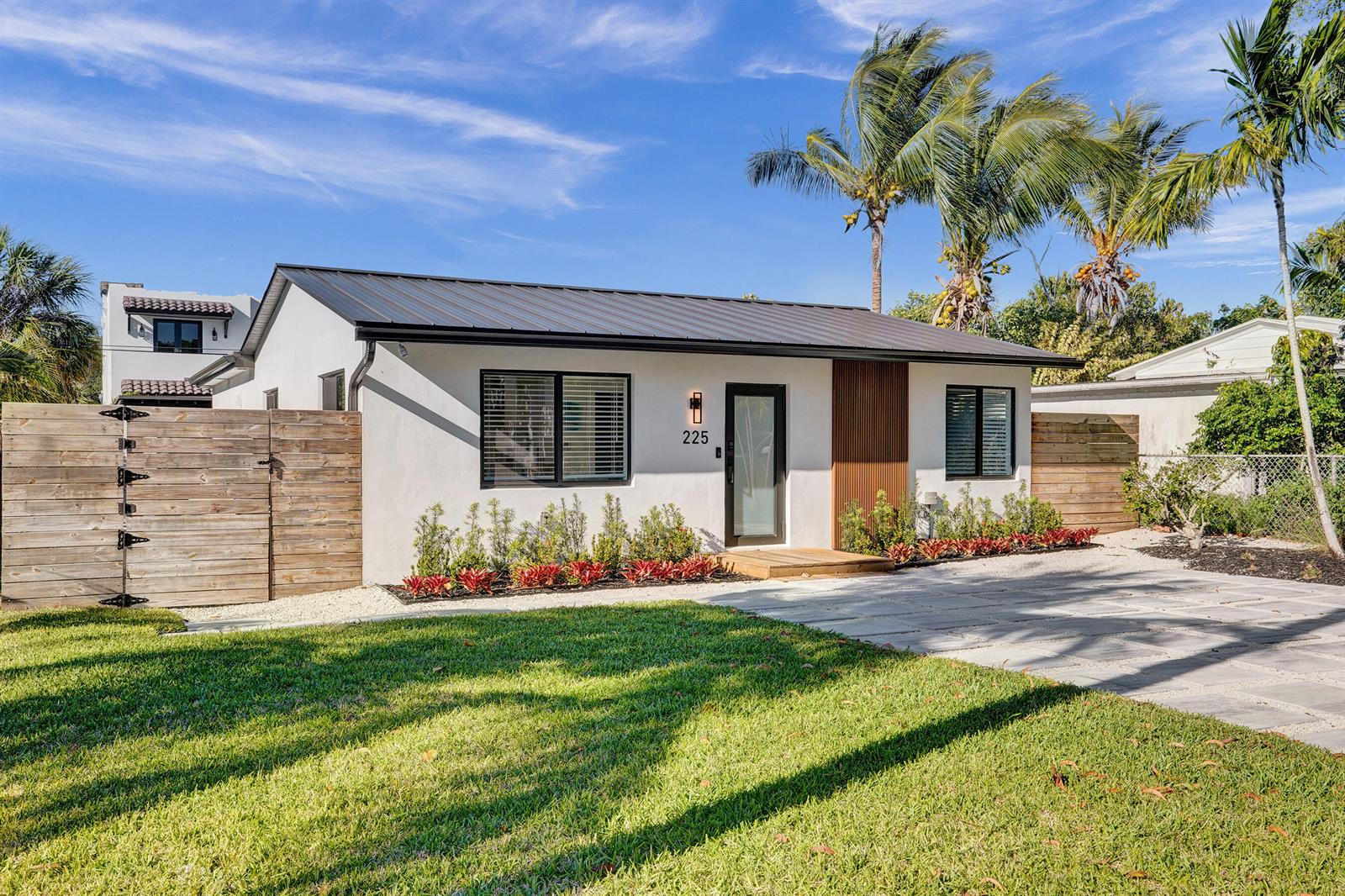 A modern, white single-story house with a metal roof, wood accents, and a wooden fence — 225 NE 10th Street, Delray Beach FL 33444, DELRAY BEACH, FL