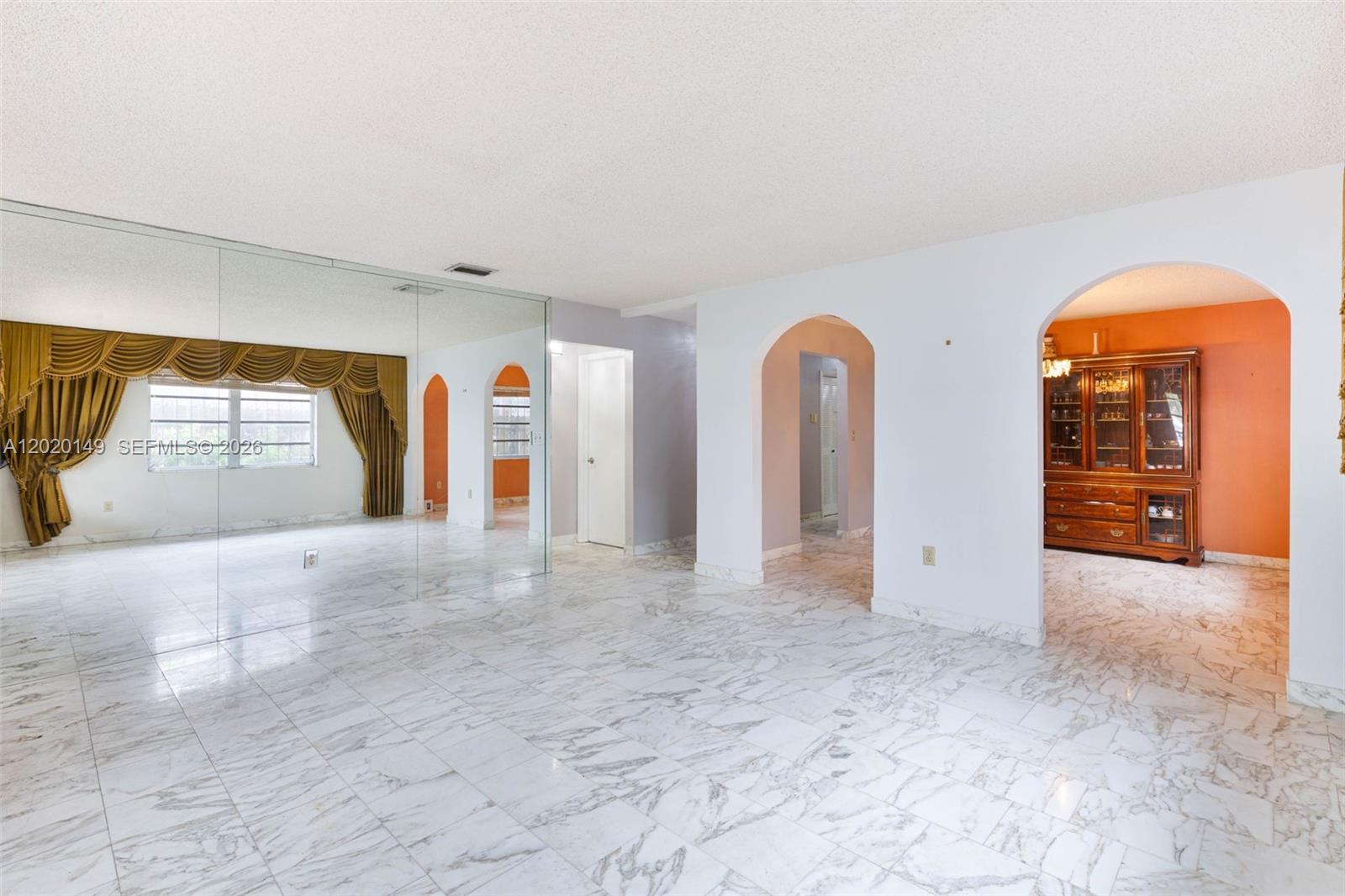 A bright room features white marble floors, arched doorways, and a large mirrored wall — 320 NW 61st Ave, Miami FL 33126, MIAMI, FL