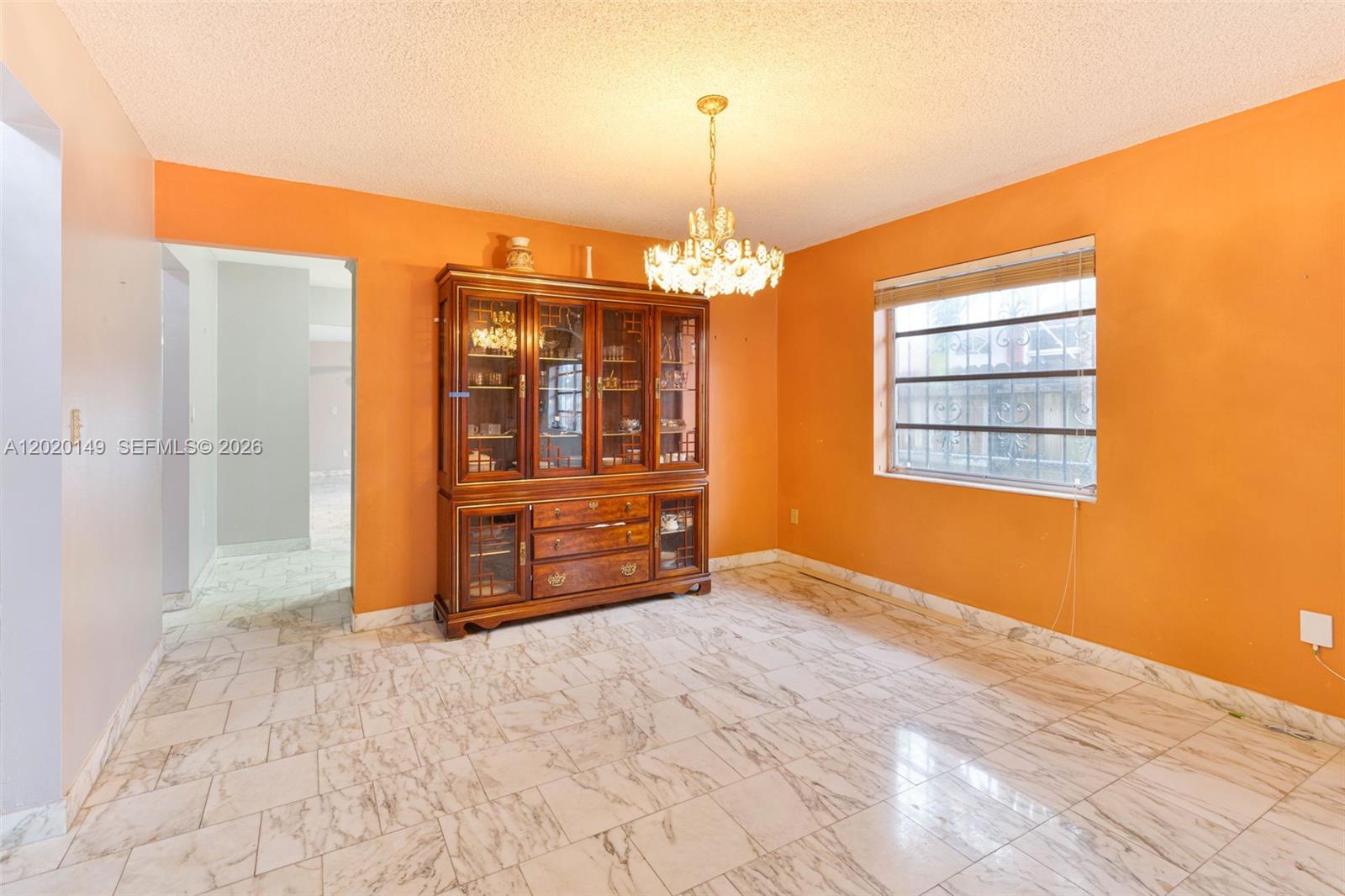 A dining room features orange walls, a large wooden hutch, and white marble-patterned tile flooring — 320 NW 61st Ave, Miami FL 33126, MIAMI, FL