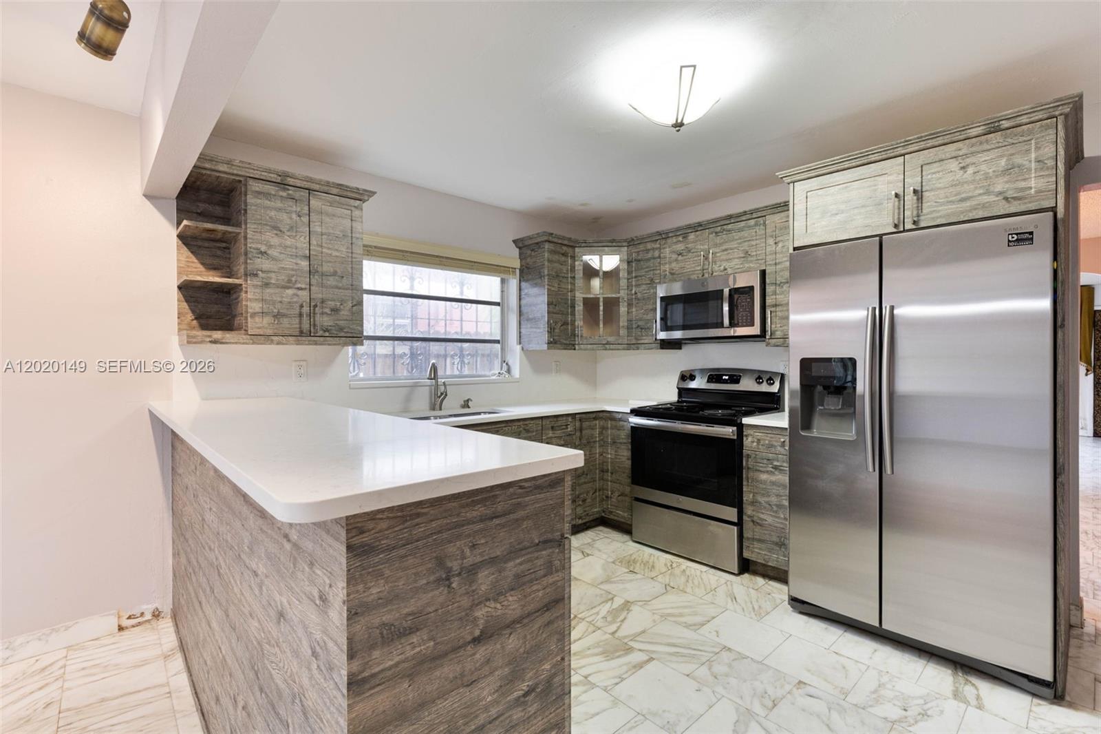 A kitchen features wood-grain cabinets, stainless steel appliances, white countertops, and light-colored tile flooring — 320 NW 61st Ave, Miami FL 33126, MIAMI, FL