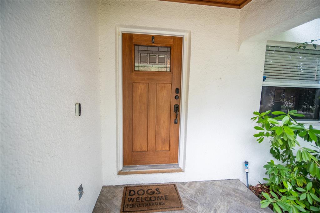A wooden front door with a glass pane is set in a white stucco entryway — 2429 S BROWN AVENUE, ORLANDO, FL