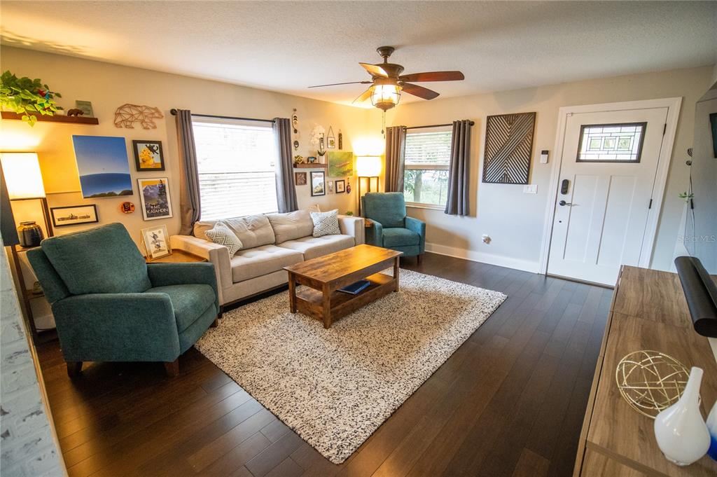 A living room features a beige sofa, two teal armchairs, a coffee table, and hardwood floors — 2429 S BROWN AVENUE, ORLANDO, FL