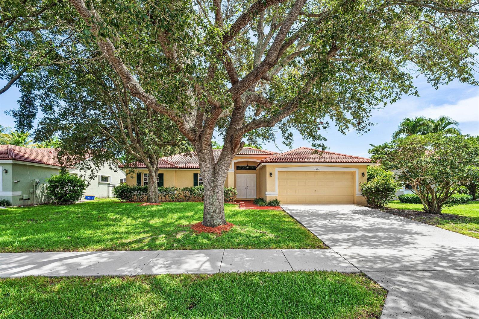 A single-story house with a tile roof, two-car garage, and a large tree in front — 4824 S Lee Road, Delray Beach FL 33445, DELRAY BEACH, FL