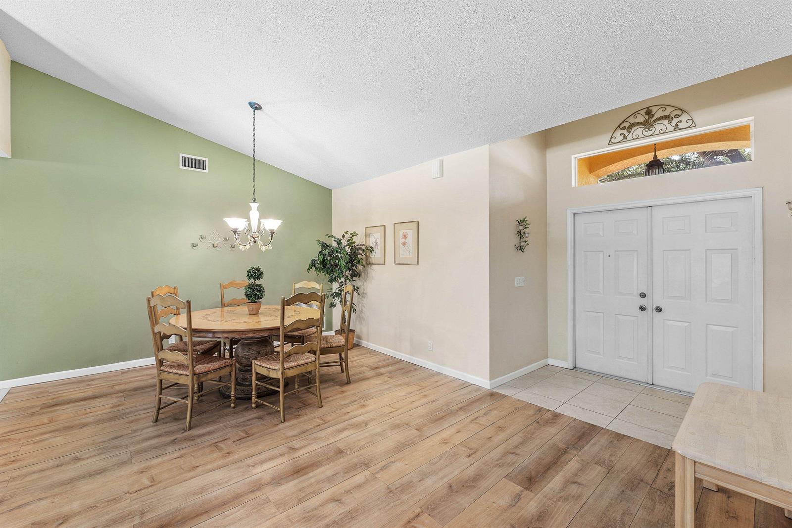 A dining area with a green accent wall, wooden floors, and a double-door entryway — 4824 S Lee Road, Delray Beach FL 33445, DELRAY BEACH, FL