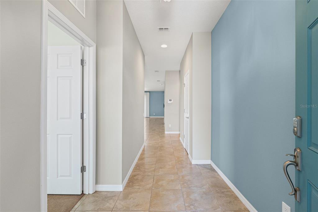 A tiled hallway leads from a blue front door toward a distant living area — 5524 107TH TERRACE E, PARRISH, FL