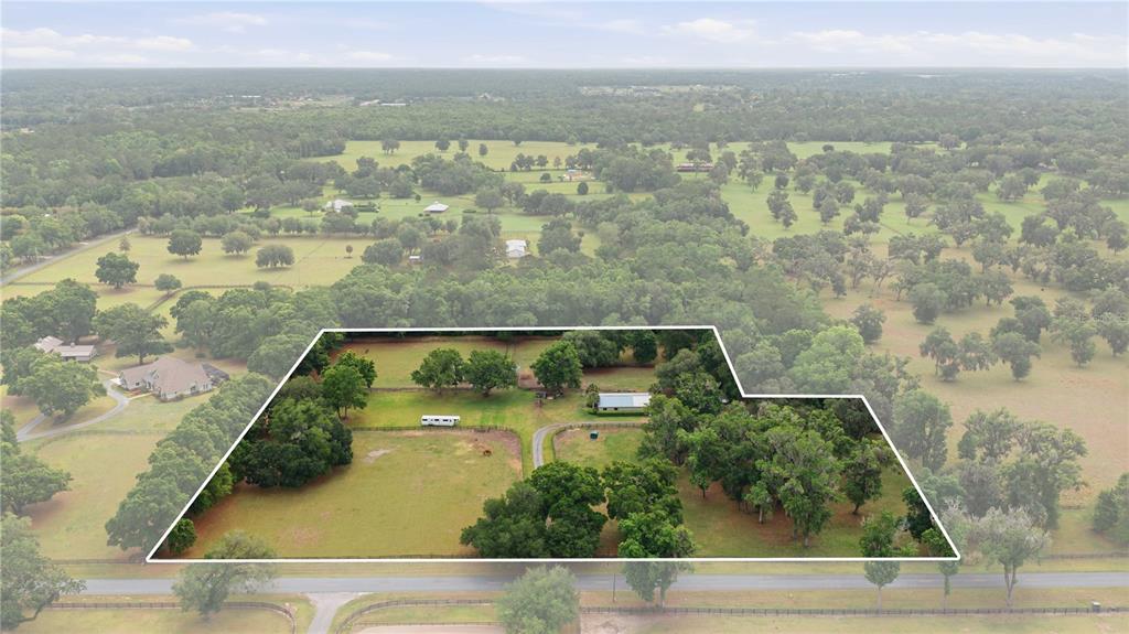 An aerial view shows a fenced rural property with trees, a house, and a trailer — 5999 NW 90TH AVENUE, OCALA, FL