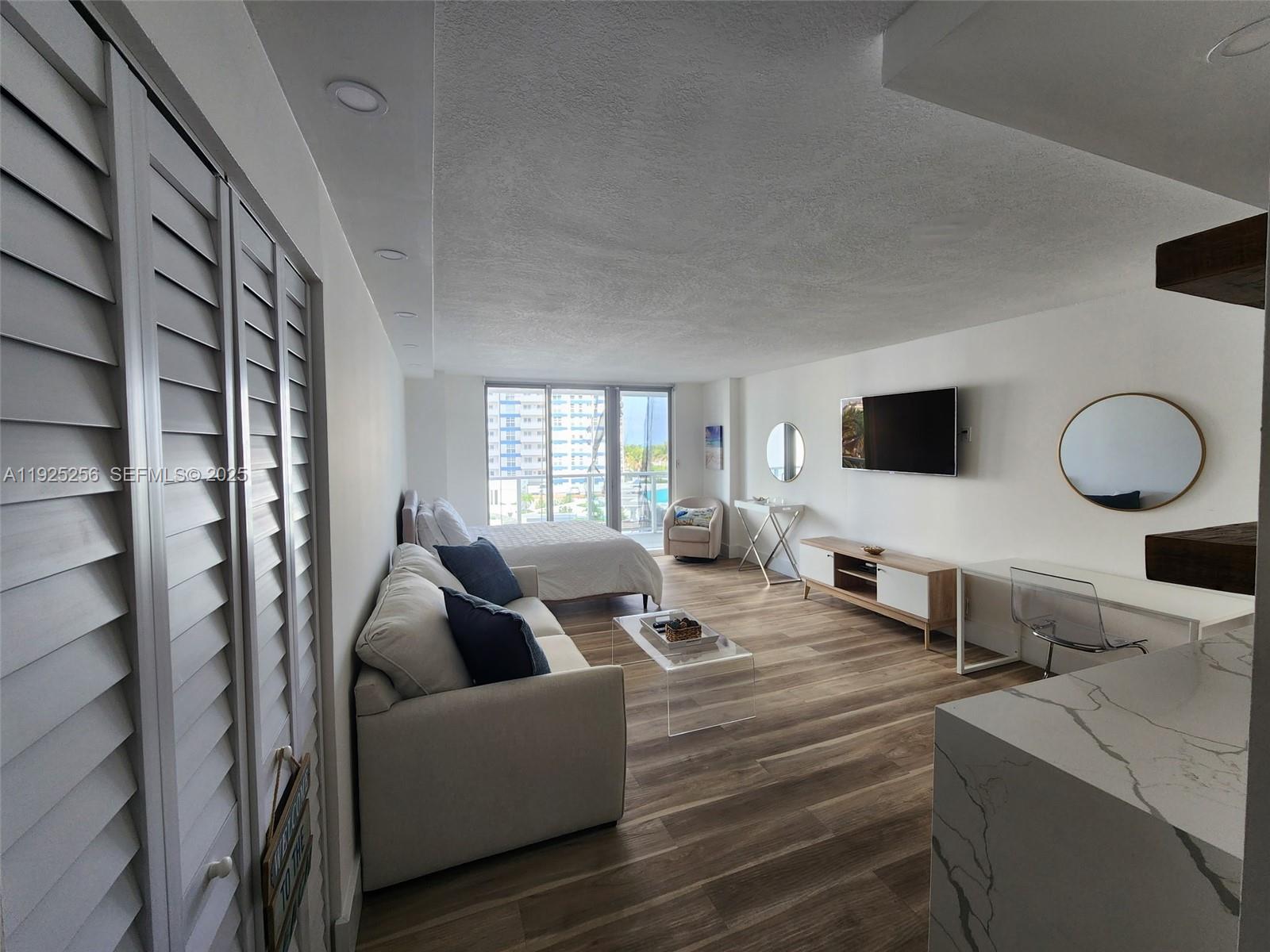 This studio apartment features a living area, bedroom, and kitchen with wood-look flooring — 3180 S Ocean Dr # 307, Hallandale Beach FL 33009, HALLANDALE BEACH, FL