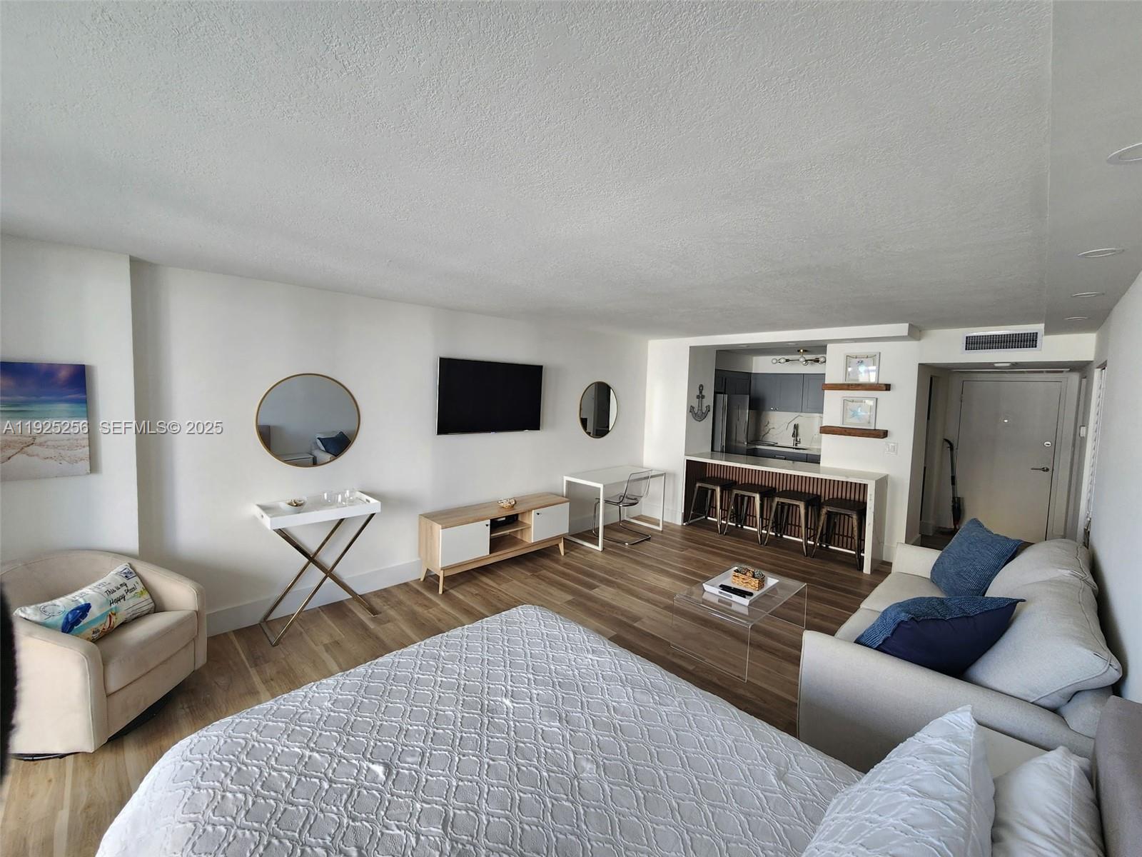 A studio apartment features a bed, sofa, kitchenette with a breakfast bar, and wood flooring — 3180 S Ocean Dr # 307, Hallandale Beach FL 33009, HALLANDALE BEACH, FL