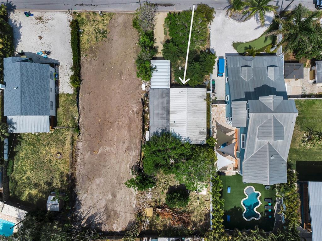 An aerial view shows a vacant lot situated between two residential properties with swimming pools — 1213 BAY PALM BOULEVARD, INDIAN ROCKS BEACH, FL