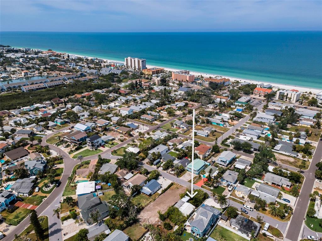 An aerial view shows a coastal neighborhood with a blue house highlighted by an arrow — 1213 BAY PALM BOULEVARD, INDIAN ROCKS BEACH, FL