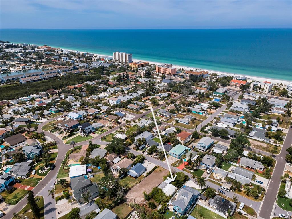 An aerial view shows a coastal neighborhood with a white arrow pointing toward a property — 1213 BAY PALM BOULEVARD, INDIAN ROCKS BEACH, FL
