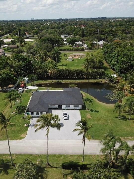 An aerial view shows a single-story house with a dark roof, driveway, and pond — 11701 SW 21st Ct, Davie FL 33325, DAVIE, FL