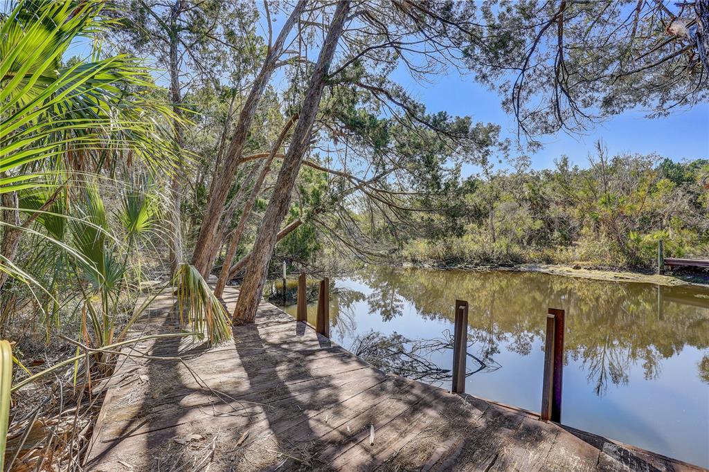 A wooden dock extends over a calm, murky waterway surrounded by trees and vegetation — 6392 S WESTVIEW DRIVE, HOMOSASSA, FL