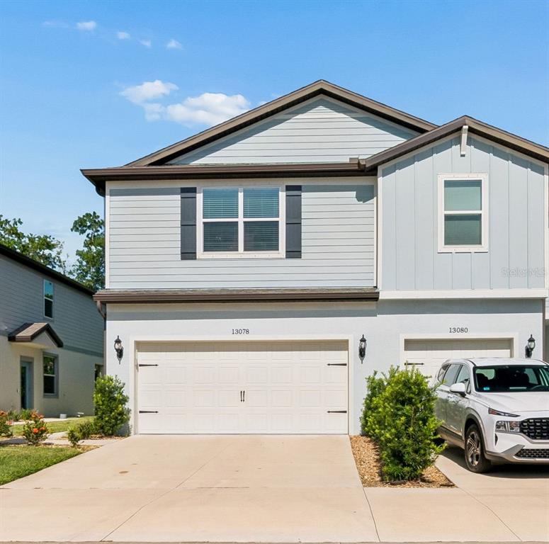A two-story house with light blue siding and a two-car garage under a clear sky — 13078 STILLMONT PLACE, TAMPA, FL
