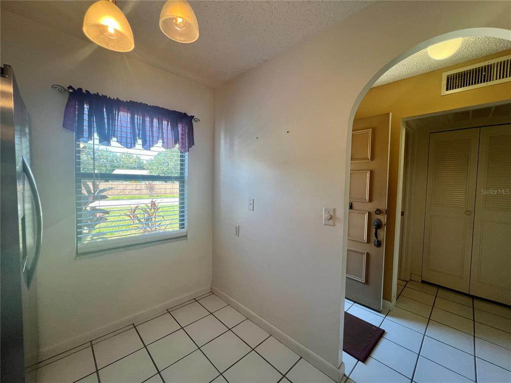 A tiled kitchen nook features a window with a purple valance and an arched doorway — 2989 FLINT DRIVE N, CLEARWATER, FL