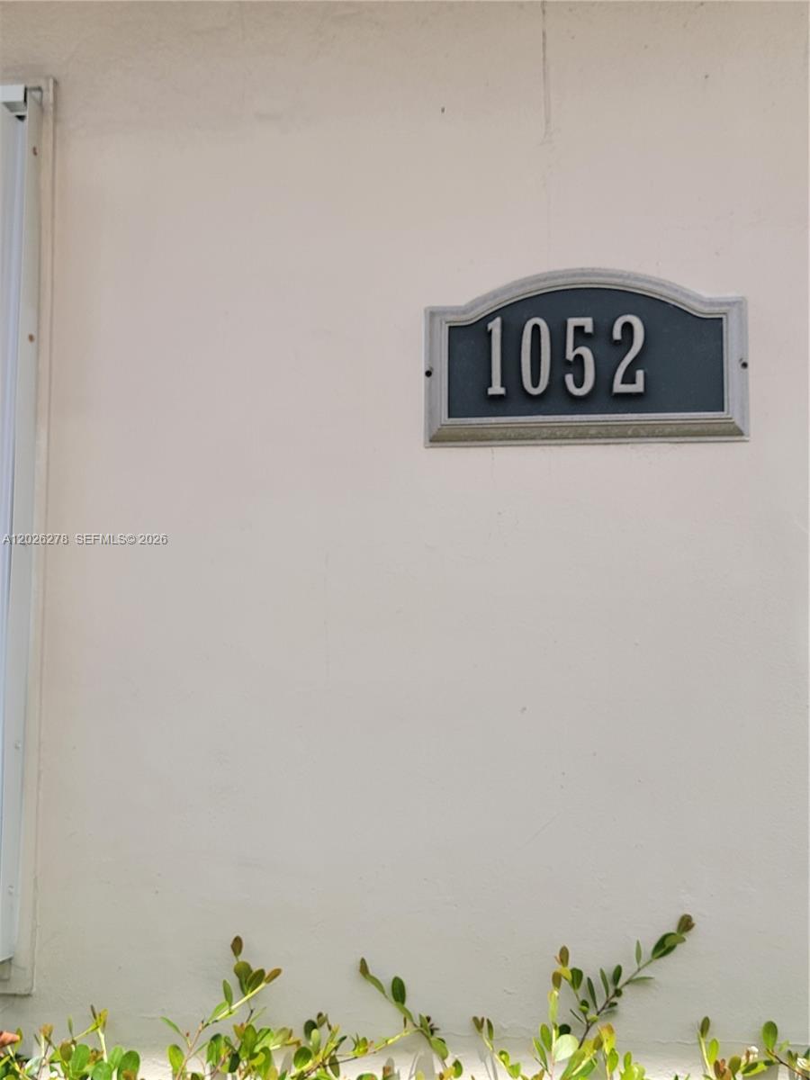 A house number plaque reading 1052 is mounted on a plain, light-colored exterior wall — 1052 SW 79th Ave, Miami FL 33144, MIAMI, FL