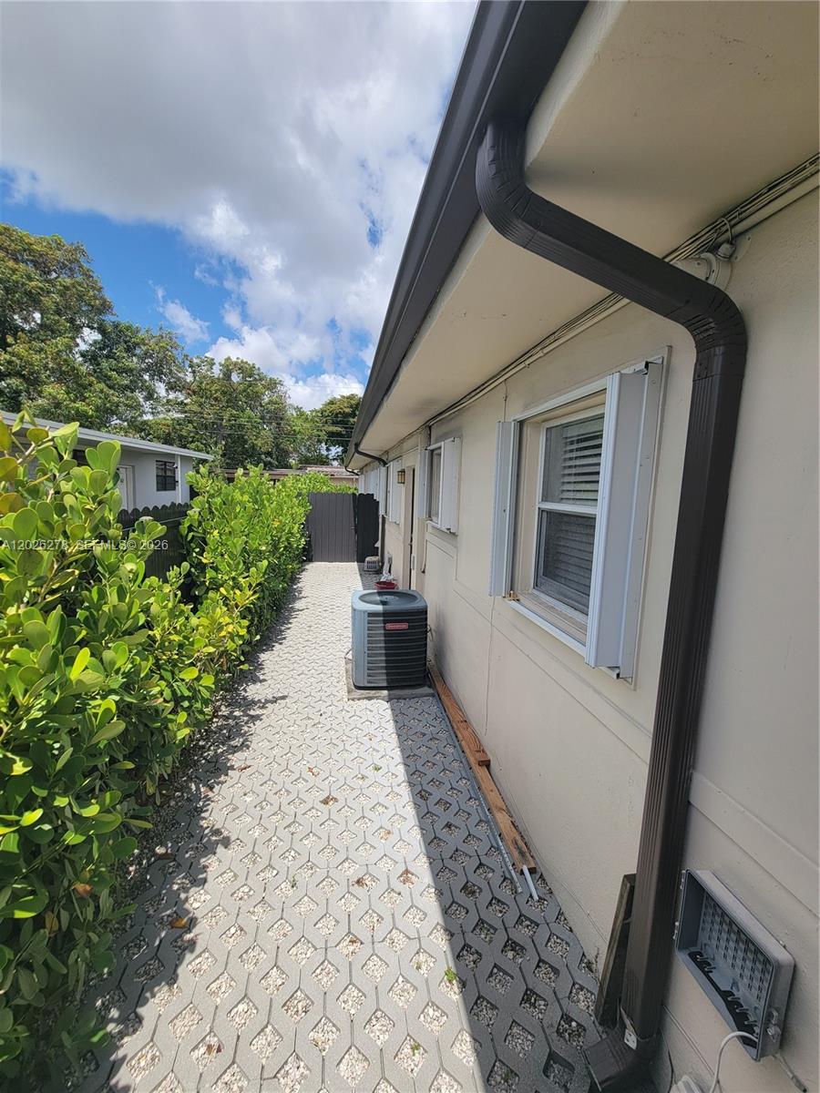 A narrow side yard features a paved walkway, a central air conditioning unit, and landscaping — 1052 SW 79th Ave, Miami FL 33144, MIAMI, FL