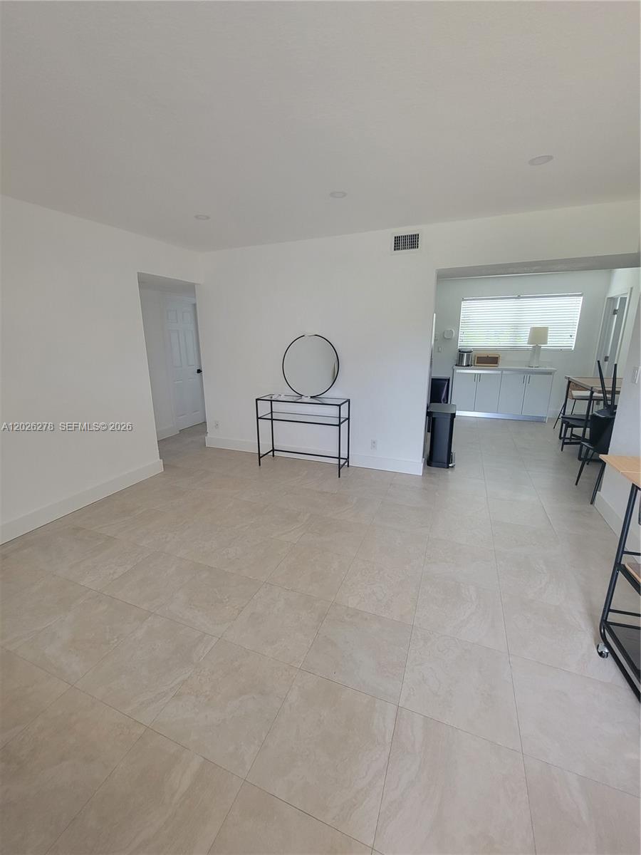 A bright, open-concept room features white walls, light tile flooring, and a metal console table — 1052 SW 79th Ave, Miami FL 33144, MIAMI, FL