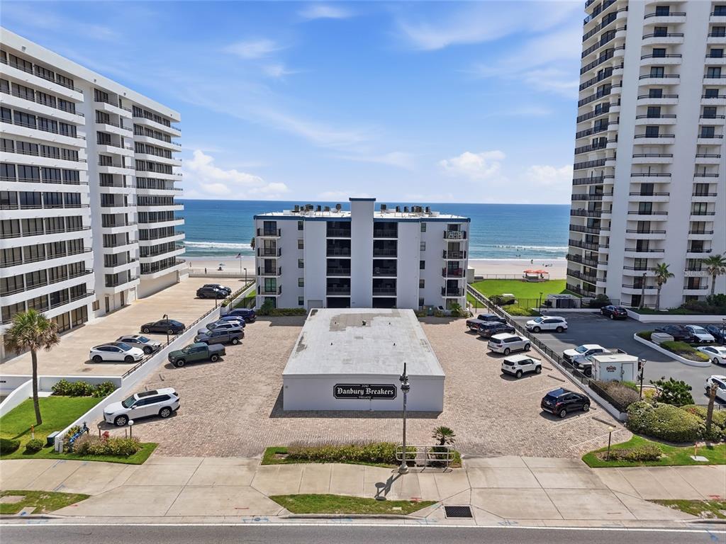 An aerial view shows a parking lot in front of a beachside apartment building — 3747 S ATLANTIC AVENUE UNIT 4050, DAYTONA BEACH, FL