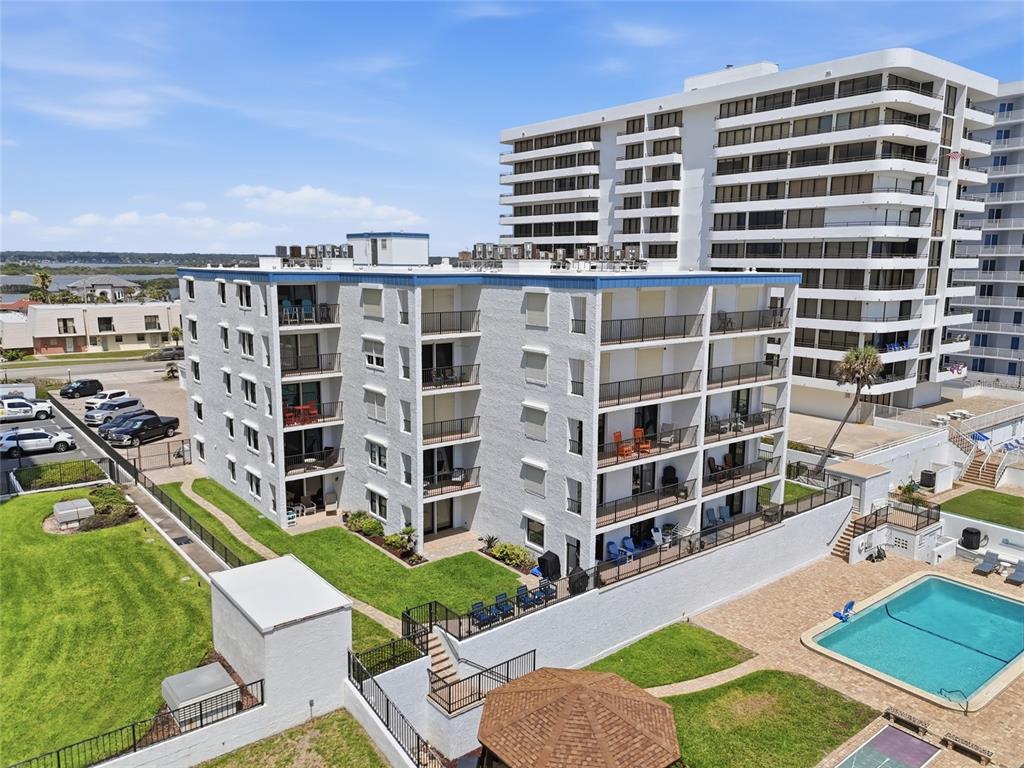 An aerial view shows a multi-story apartment building with balconies, a swimming pool, and parking — 3747 S ATLANTIC AVENUE UNIT 4050, DAYTONA BEACH, FL