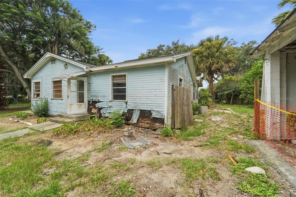 A light blue, single-story house with visible exterior wood siding damage and a small porch — 495 NORTH STREET, DE LEON SPRINGS, FL