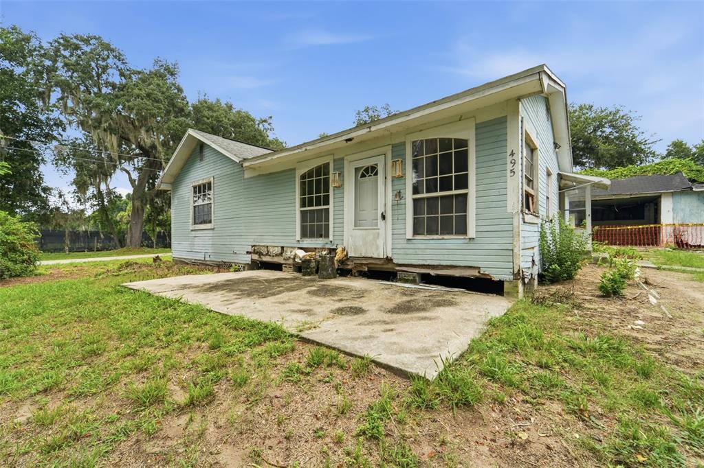 A light blue, single-story house with a concrete patio and visible foundation damage — 495 NORTH STREET, DE LEON SPRINGS, FL