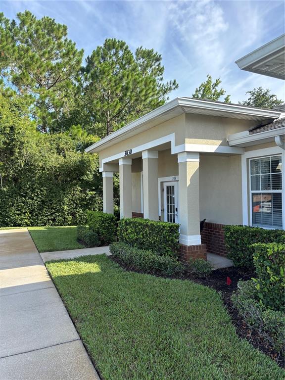 A beige building exterior with a covered entryway, white columns, and a manicured lawn — 3830 TURMAN LOOP, WESLEY CHAPEL, FL
