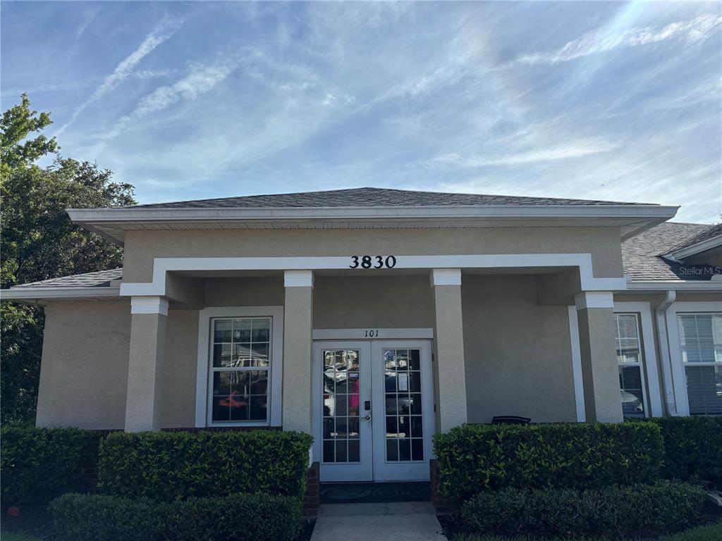 The exterior view shows a beige commercial building entrance with double glass doors and columns — 3830 TURMAN LOOP, WESLEY CHAPEL, FL