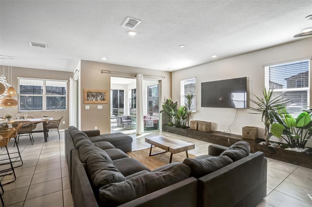 A living room features a large sectional sofa, a wall-mounted television, and indoor planter boxes — 8918 TROPICAL HAVEN COURT, KISSIMMEE, FL