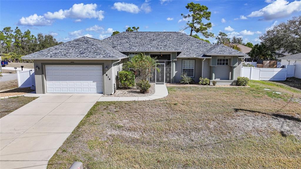 A single-story house with a two-car garage, gray roof, and a front walkway — 1816 NORTHLAND AVENUE, NORTH PORT, FL