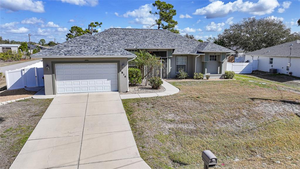 A single-story house with a two-car garage, gray shingled roof, and a concrete driveway — 1816 NORTHLAND AVENUE, NORTH PORT, FL
