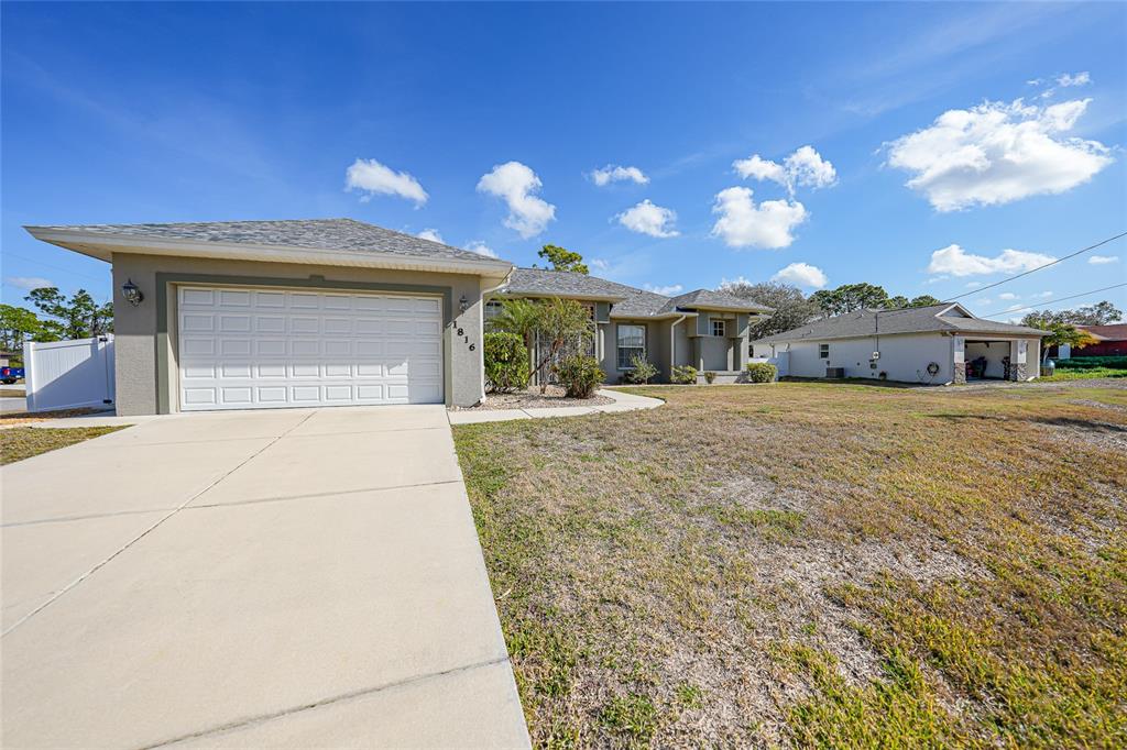 A single-story house with a white garage door, beige siding, and a concrete driveway — 1816 NORTHLAND AVENUE, NORTH PORT, FL
