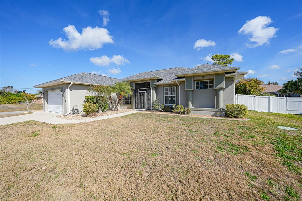 A single-story house with a gray shingled roof, beige stucco exterior, and a two-car garage — 1816 NORTHLAND AVENUE, NORTH PORT, FL