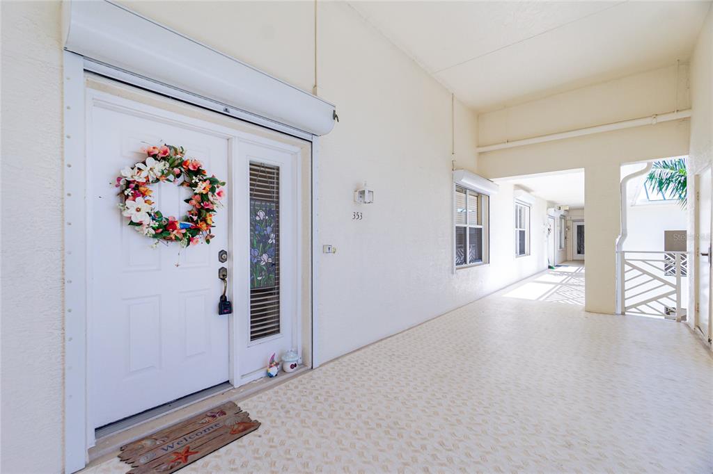 A white front door with a floral wreath opens onto a covered outdoor walkway — 200 HARBOR WALK DRIVE UNIT 353, PUNTA GORDA, FL
