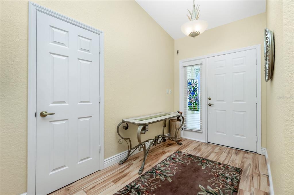 An entryway features a white front door with a sidelight, a console table, and wood-look flooring — 200 HARBOR WALK DRIVE UNIT 353, PUNTA GORDA, FL
