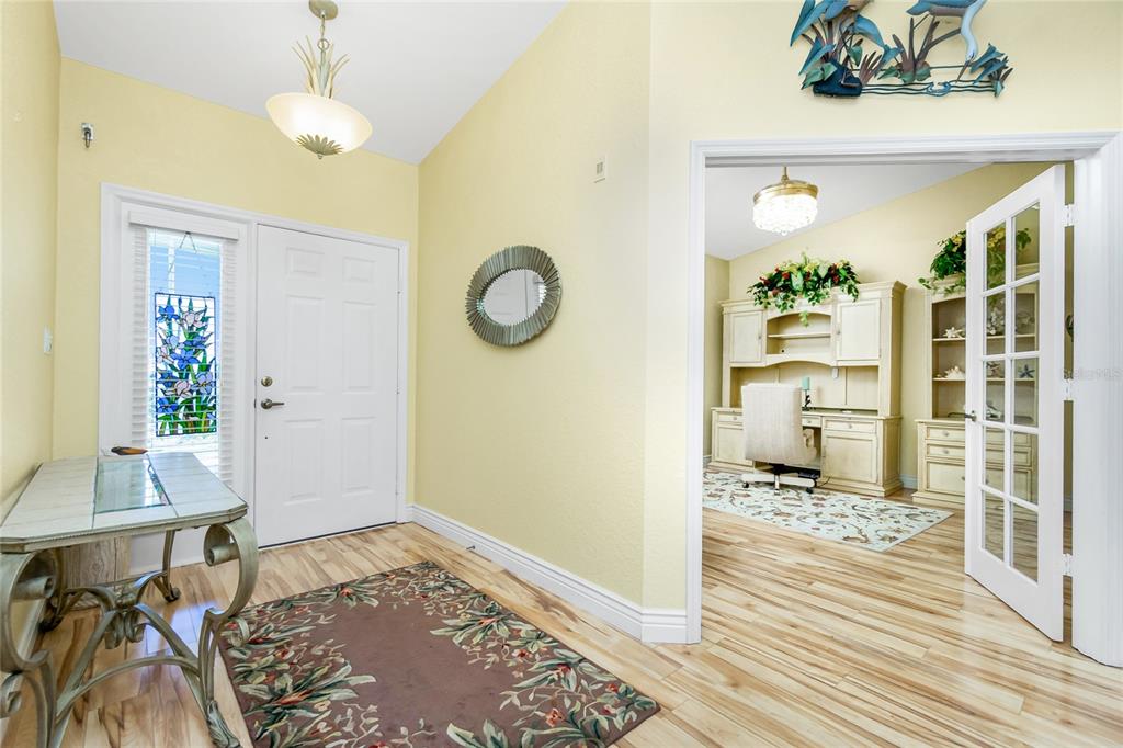 An entryway with light yellow walls, a white front door, and a home office visible — 200 HARBOR WALK DRIVE UNIT 353, PUNTA GORDA, FL