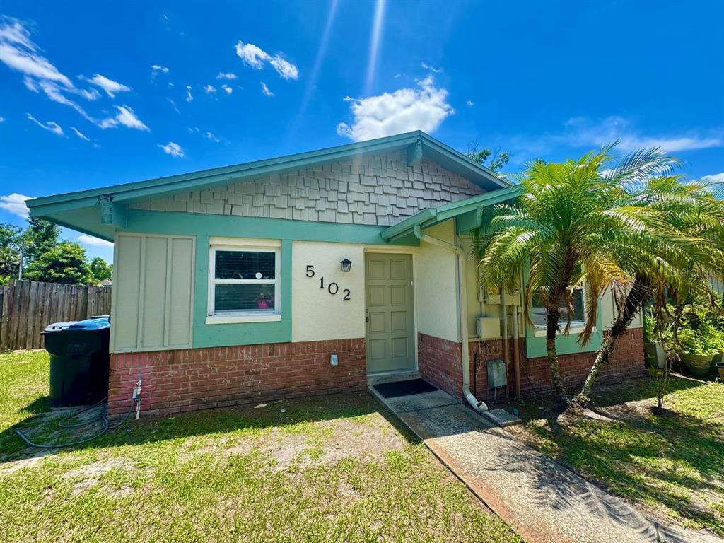 A single-story house with a brick base, teal trim, and a palm tree in front — 5102 LAWNTON COURT, TAMPA, FL