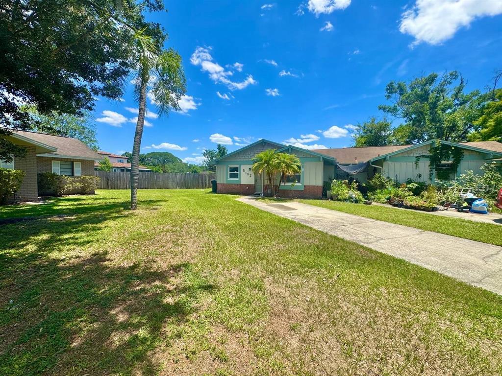 A single-story house with a concrete driveway and a grassy front yard under a blue sky — 5102 LAWNTON COURT, TAMPA, FL