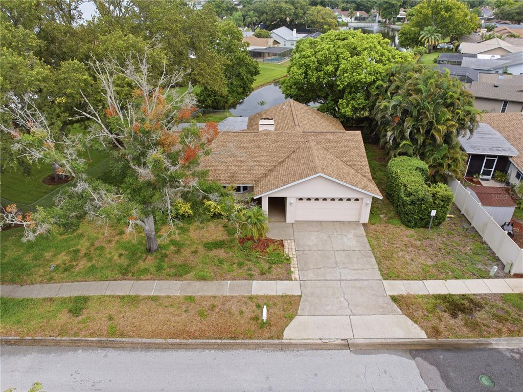 An aerial view shows a single-story house with a tan roof, garage, and front lawn — 9743 106TH AVENUE, LARGO, FL