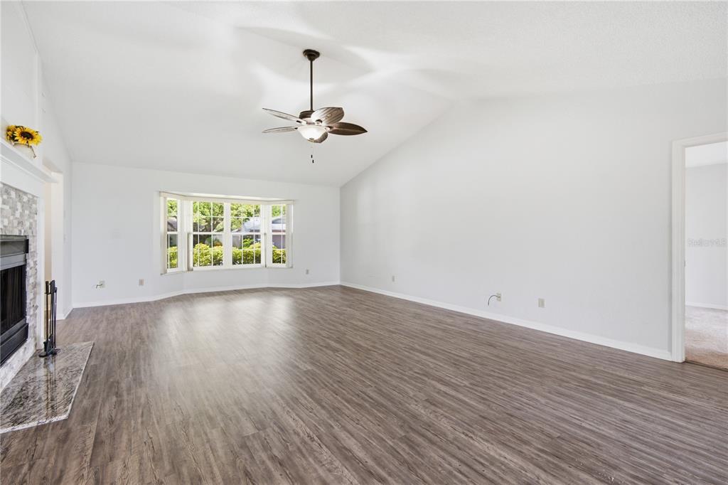 A spacious living room features light gray walls, wood-look flooring, a fireplace, and vaulted ceilings — 9743 106TH AVENUE, LARGO, FL