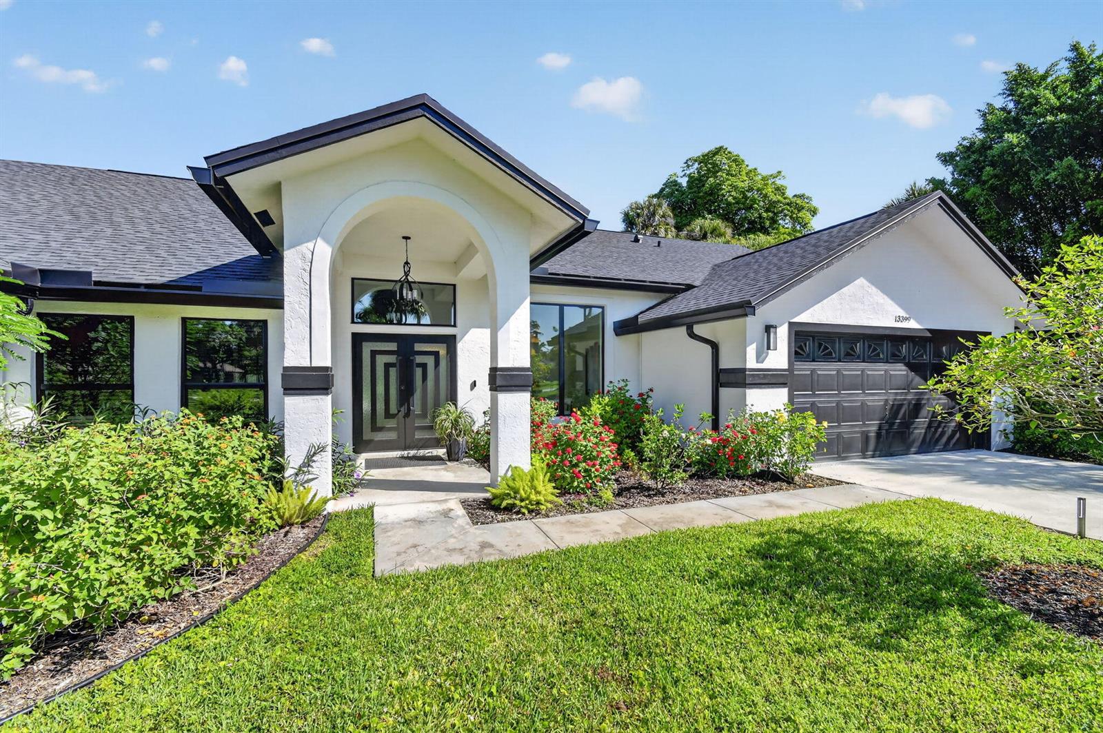A single-story house with white stucco walls, a black roof, and a covered front entryway — 13399 Doubletree Circle, Wellington FL 33414, WELLINGTON, FL