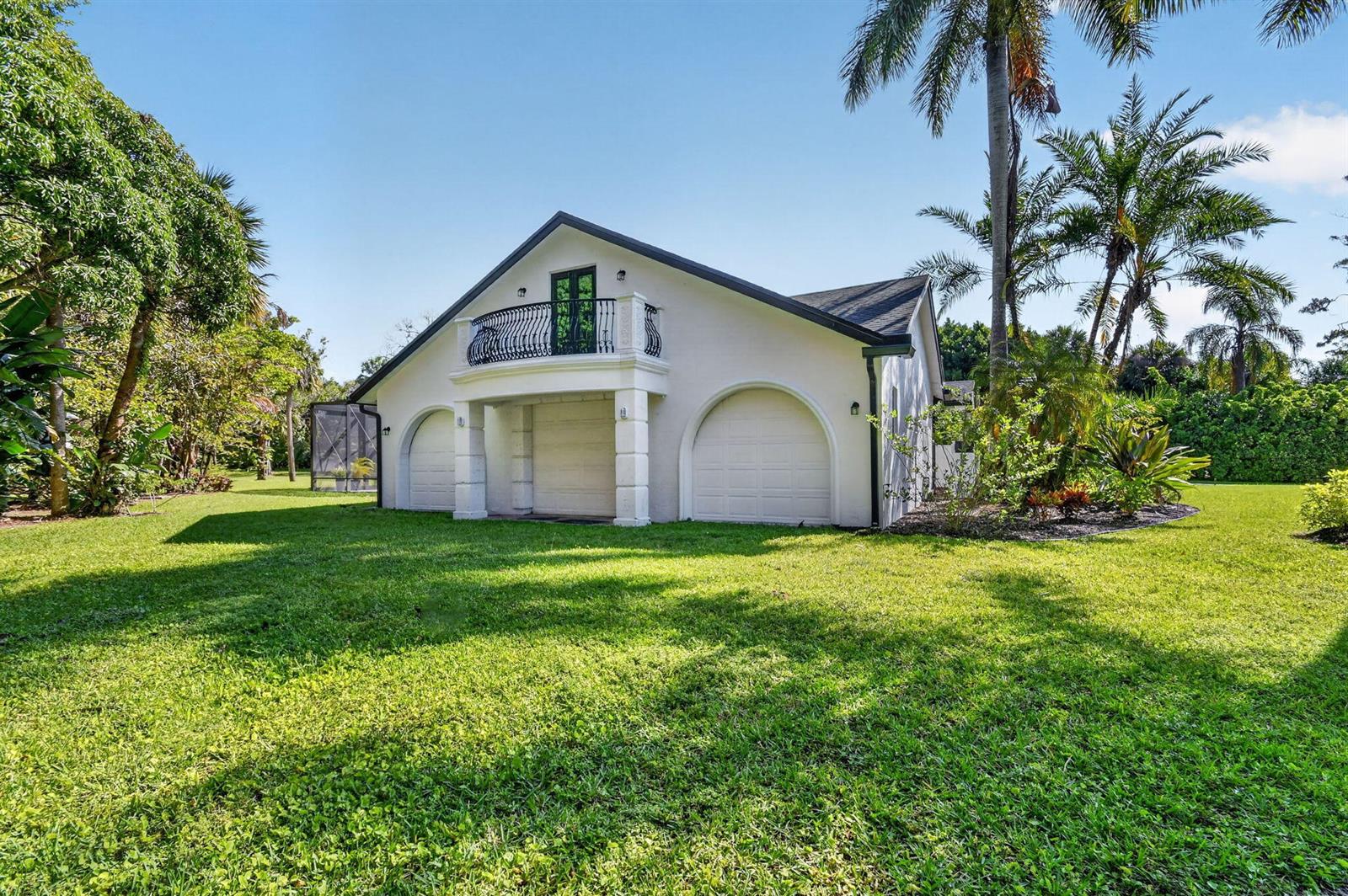 A white detached garage with three arched bays and an upper-level balcony with iron railings — 13399 Doubletree Circle, Wellington FL 33414, WELLINGTON, FL