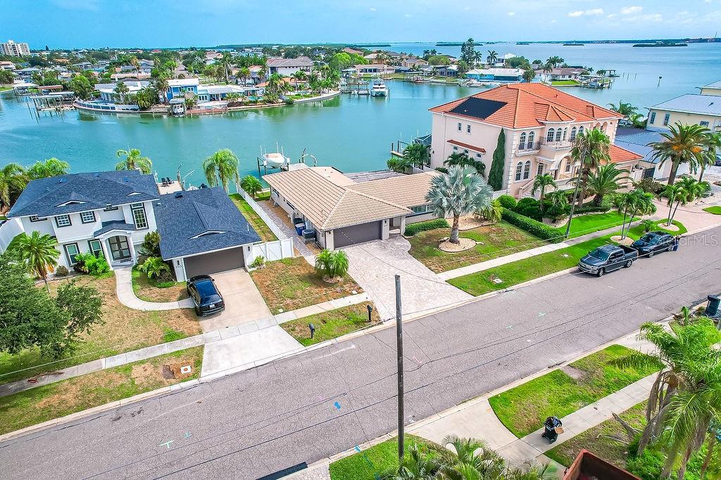 An aerial view shows two waterfront houses with driveways, lawns, and a canal with boats — 340 PALM ISLAND NE, CLEARWATER BEACH, FL