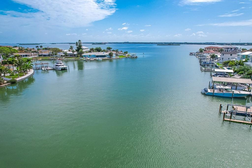 An aerial view of a canal lined with residential homes, boat docks, and moored boats — 340 PALM ISLAND NE, CLEARWATER BEACH, FL